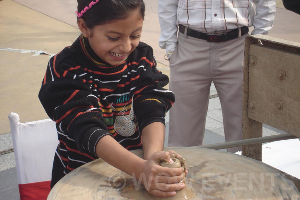 Child shaping clay on a pottery wheel at the carnival