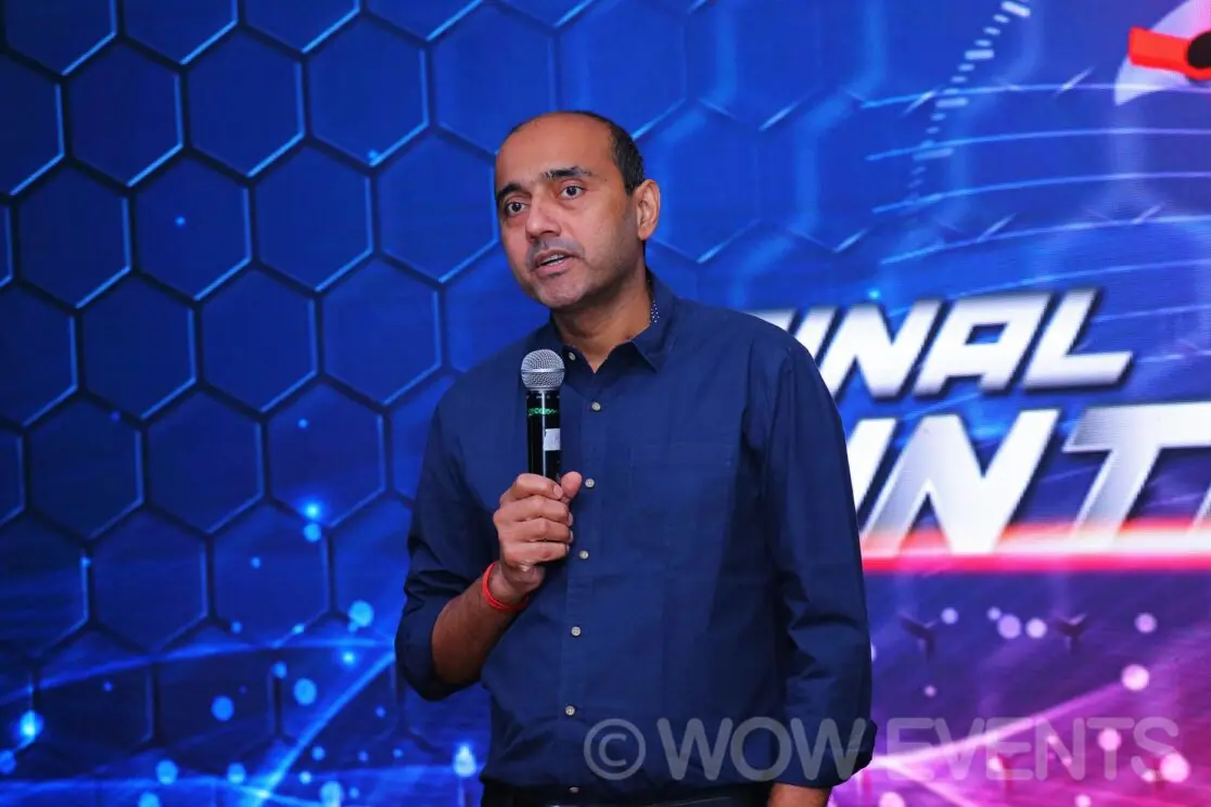 Speaker with a microphone in front of the Final Countdown screen