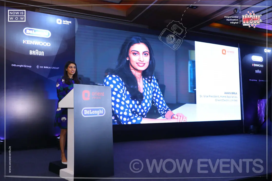 Host at a De'Longhi podium with a speaker on screen