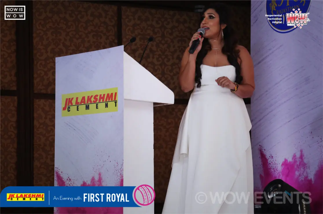 Host in a white gown at a JK Lakshmi Cement podium