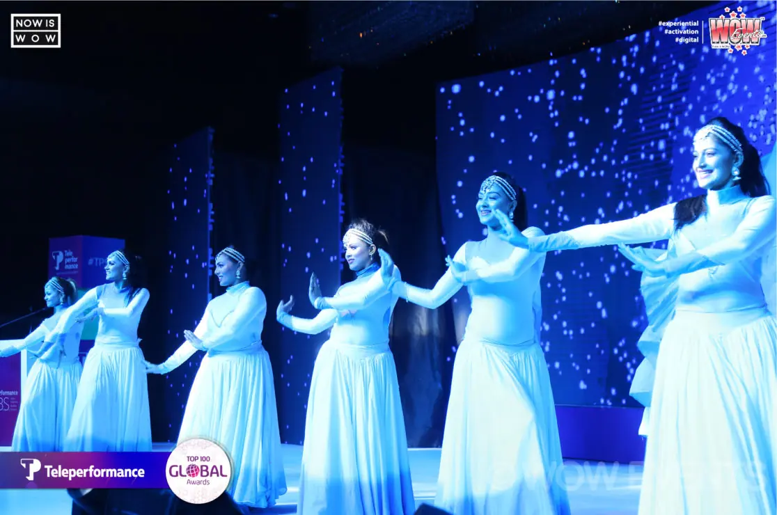 Dancers in white performing on a blue-lit stage