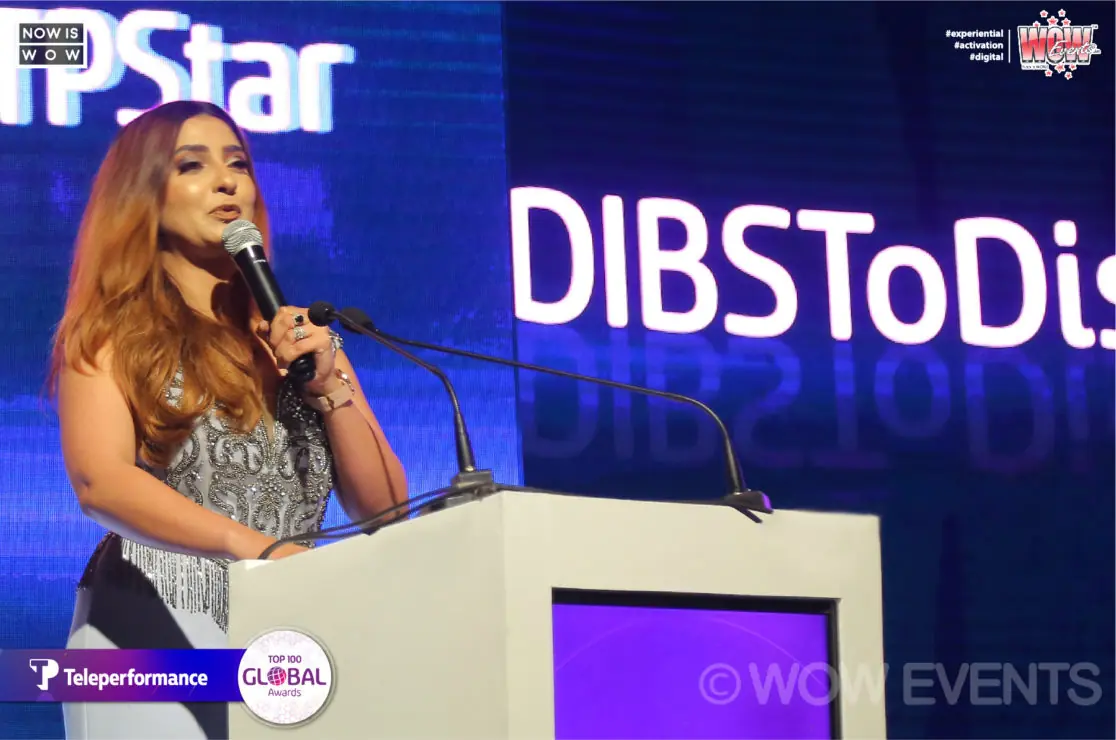 Host at a podium at the Teleperformance Top 100 Global Awards