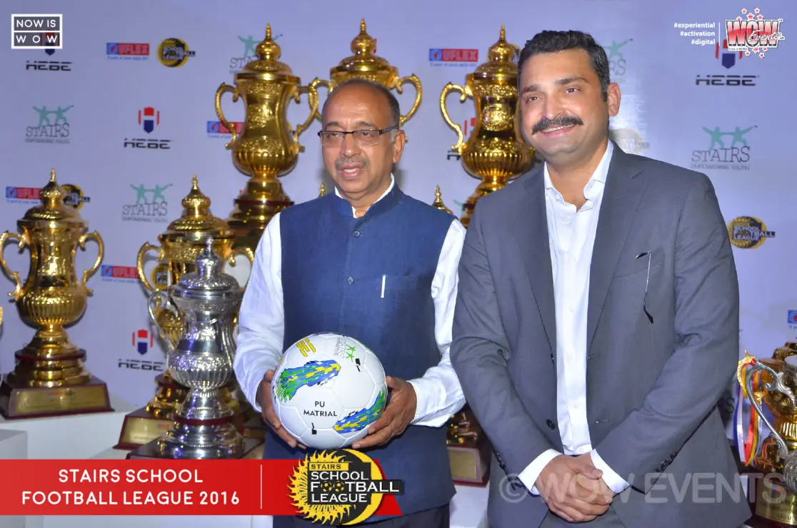 Guests holding a football beside trophies