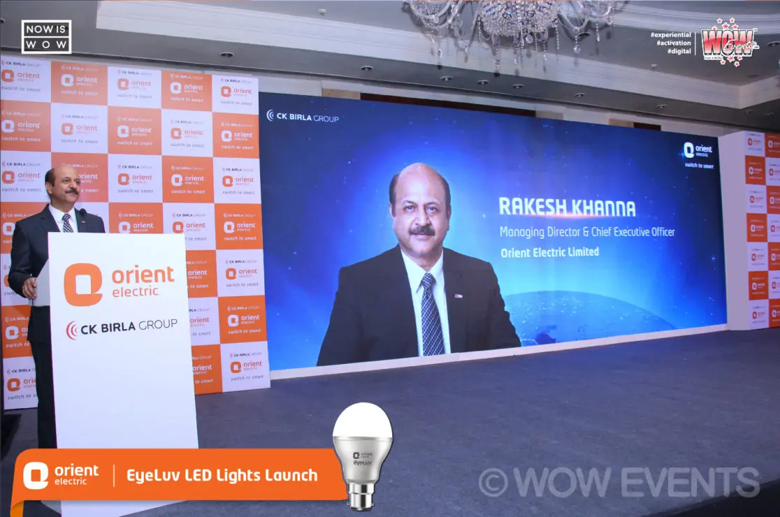 Speaker at an Orient Electric podium with a presenter on screen
