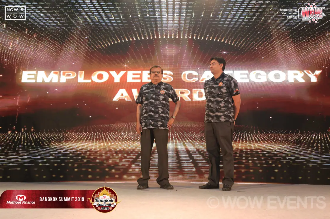 Two attendees on stage under the Employee Category Award screen