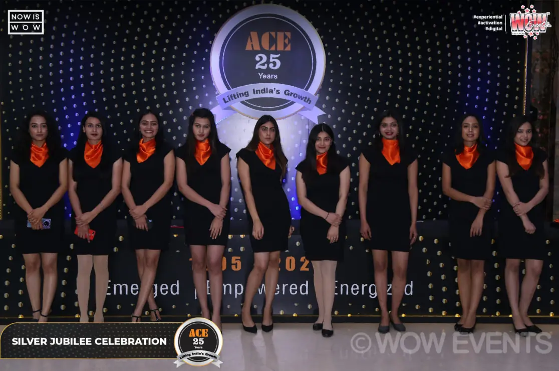 Hostesses in black dresses lined up in front of the ACE 25 years stage