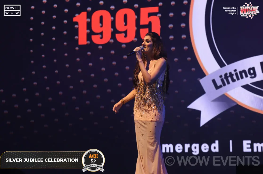 Host in a gold gown on stage at the ACE silver jubilee