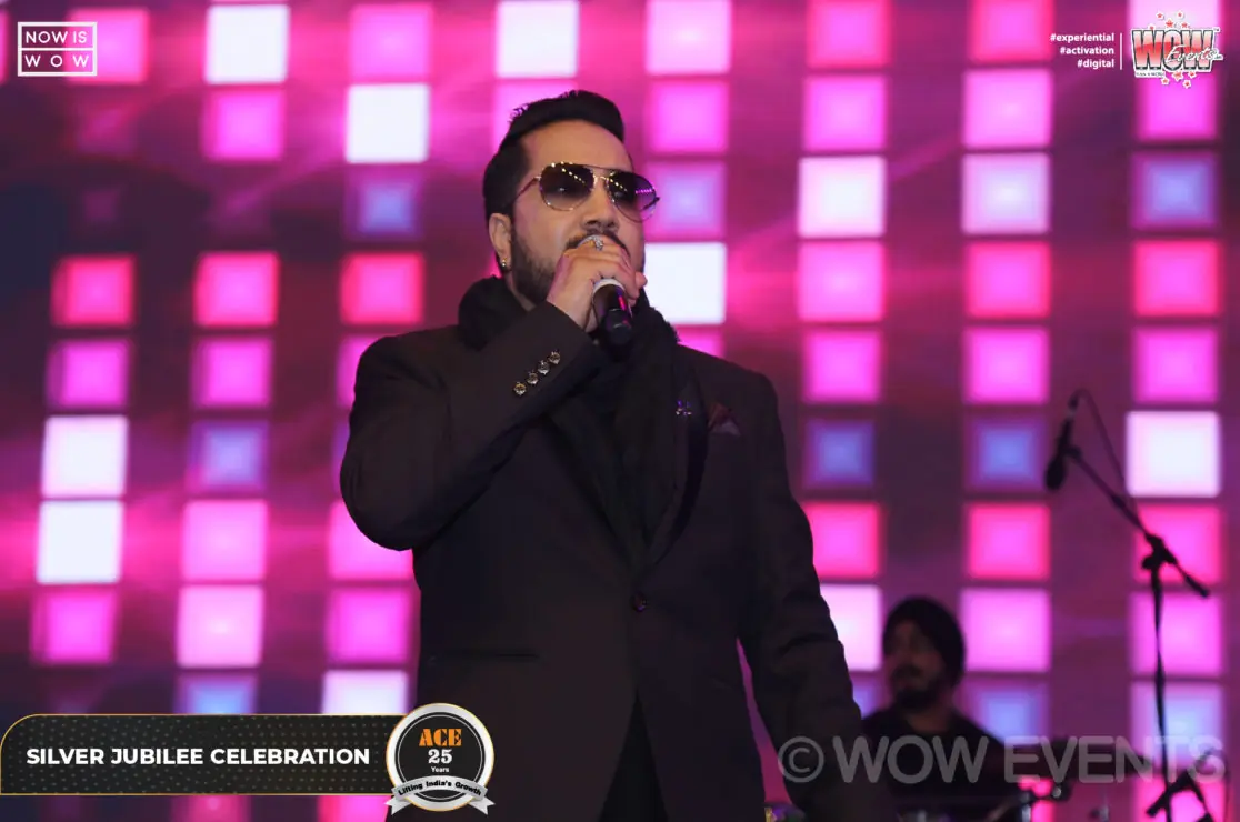 Singer in sunglasses performing in front of a pink LED wall