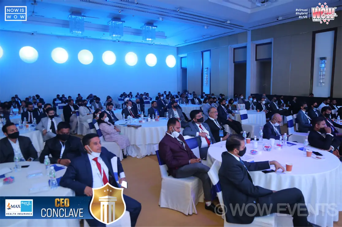 Attendees seated in a blue-lit hall at the CEO Conclave