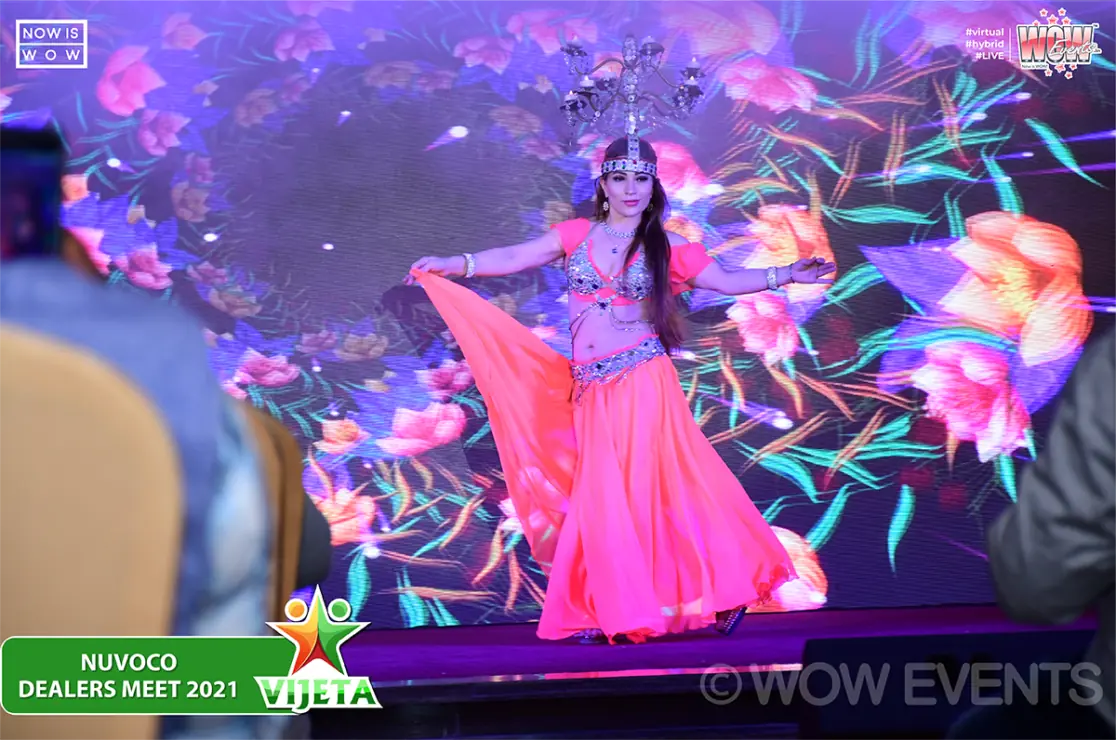 Dancer in pink performing in front of a floral screen