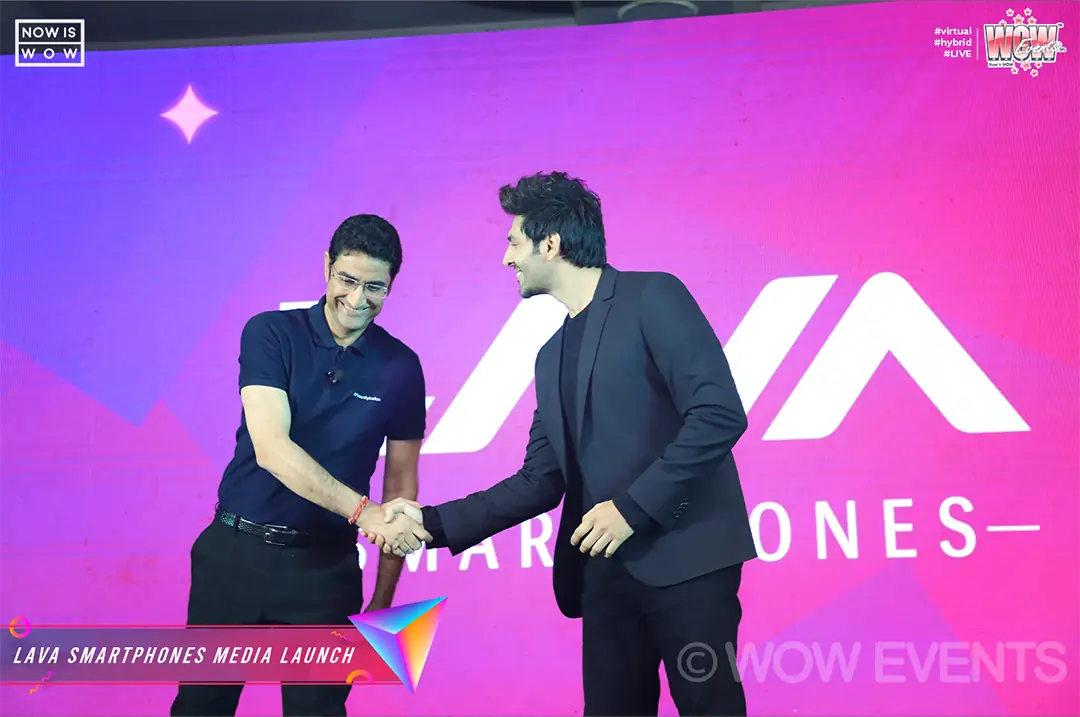 Kartik Aaryan shaking hands with a Lava executive on stage