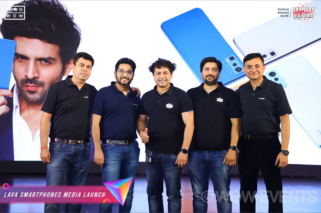 Lava team posing beside a Kartik Aaryan Blaze poster